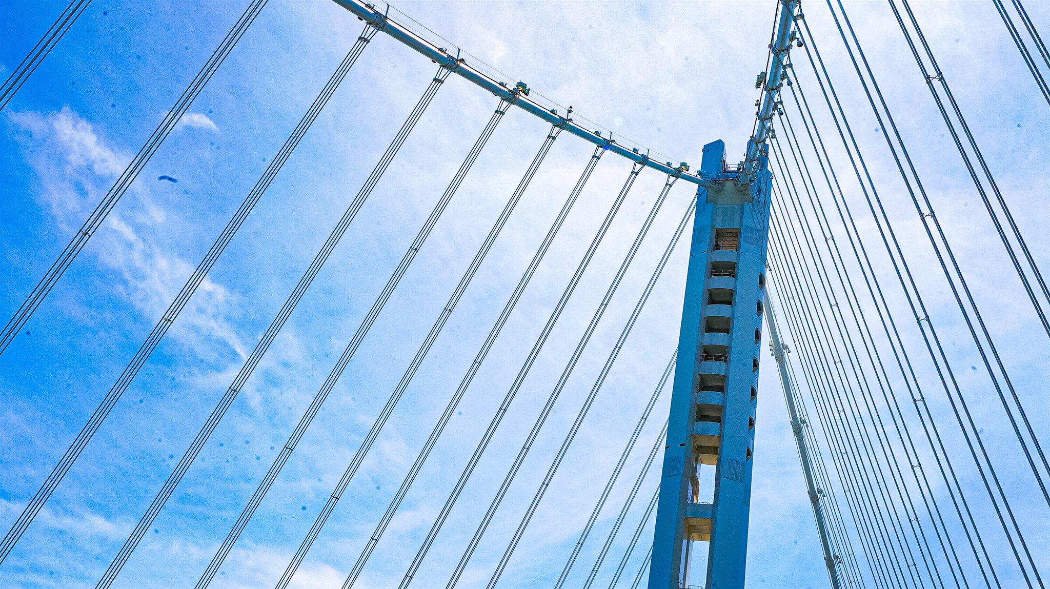 Suspension bridge tower and cables against a blue sky