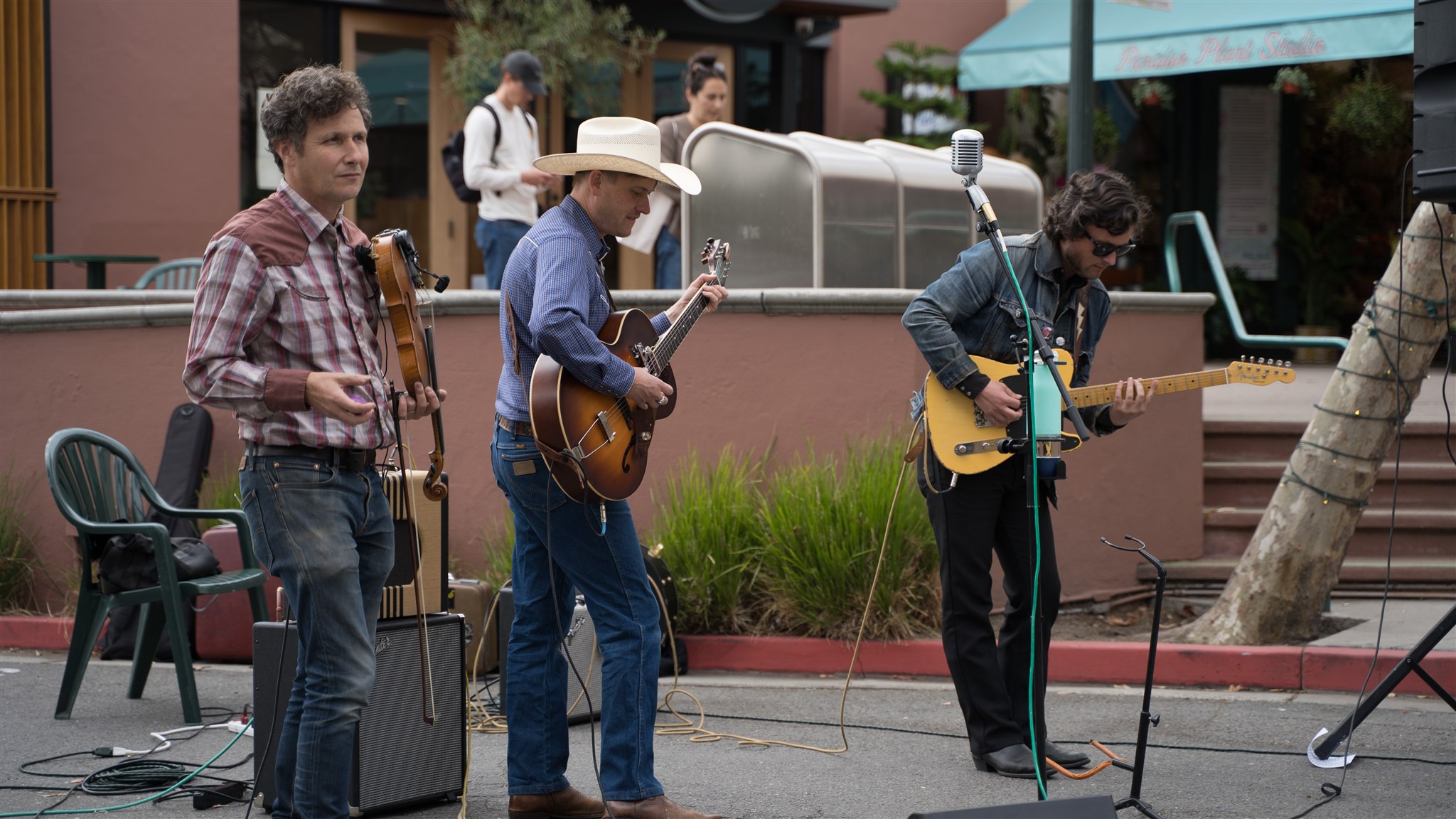 Three musicians with violin and guitars performing outdoors