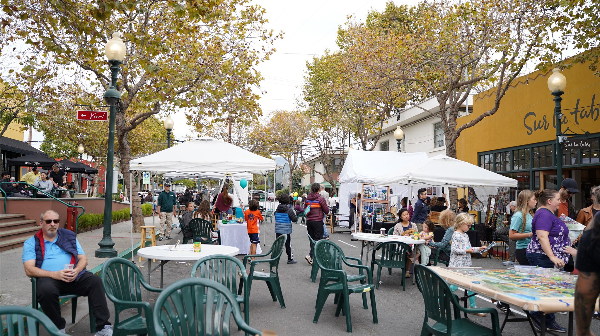 People browsing outdoor booths and making art at a community street event
