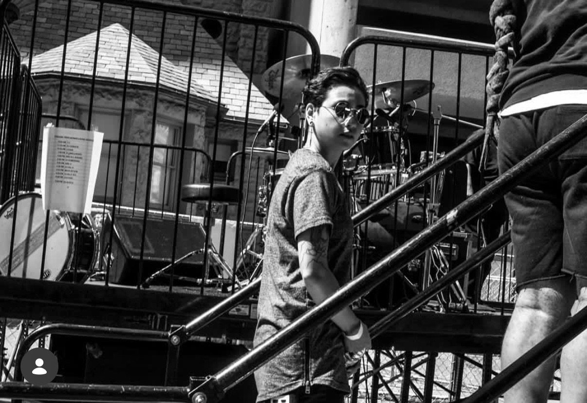 Black and white portrait beside stage stairs and a drum kit